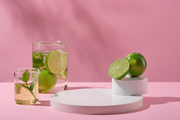 Front view lime slices and leaves in beaker with transparent liquid and empty round podium on pink background. Scene for advertising cosmetics of lime extract. Minimal concept.