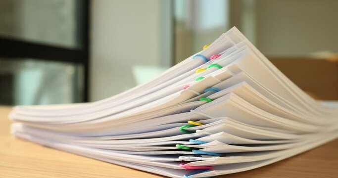 Time lapse of papers with multi-colored clips disappearing from wooden table in office. Stack of documents and accounting papers at secretary workplace