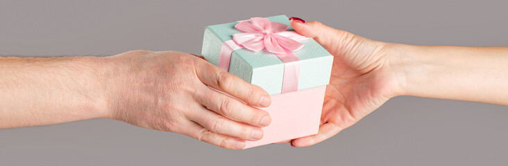 Man hands holding valentines day gift. Male and female hands holding pink gifts box. Girl gives a gift to man. Woman hands holding gift
