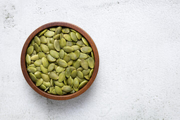 Top view of pumpkin kernels in bowl on white background