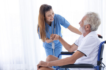 Homecare nurse staff take care elder male sitting at wheelchair happy smile together at home.