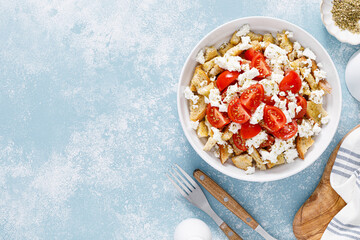 Dakos or koukouvagia salad. Classic recipe Cretan barley rusk salad with fresh tomato, mizithra cheese and oregano. Traditional mediterranean Greek cuisine. Healthy food, diet. Top view