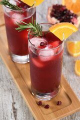 Pomegranate orange holiday punch with ice and rosemary. This is a sweet, tart and refreshing cocktail perfect for celebrating any party.