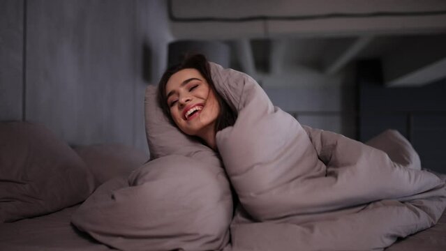 Young woman under duvet on bed