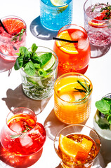 Summer cocktails drinks set. Assortment of multicolored strong and low alcoholic beverages for cocktail party. White background, hard light, shadows pattern, top view