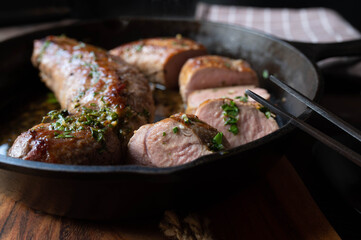Pork fillet with melted herb butter in a cast iron pan