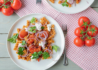 Vegetarian pasta dish with whole grain noodles, tomato sauce, cottage cheese, roasted tomatoes, red onions on a plate