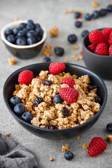 Tasty granola with berries on stone background, close up. Healthy breakfast.