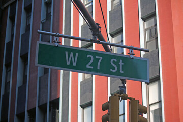 Green big West 27th Street sign hanging on a arch pole in the streets of midtown Manhattan