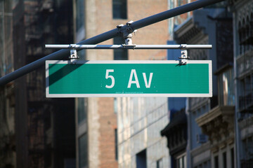 Green big 5 Av sign hanging on a arch pole in the streets of midtown Manhattan
