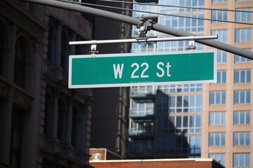 Green big West 22nd Street sign hanging on a arch pole in the streets of midtown Manhattan