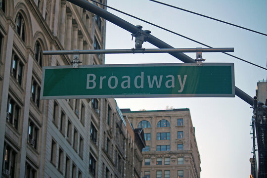 Green big Broadway Street sign hanging on a arch pole in the streets of midtown Manhattan