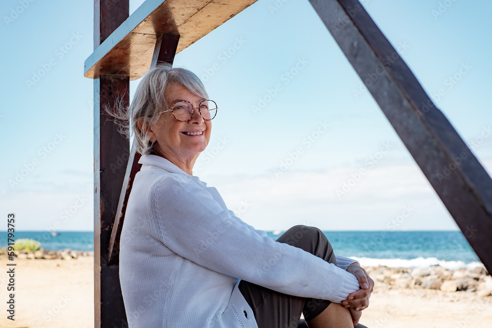 Sticker Happy senior woman in casual clothing relaxed at the beach looking away enjoying vacations and freedom during retirement - horizon over sea