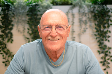 Close-up Portrait of Happy 70 Years Old Senior Man Smiling Looking at Camera. Relaxed Grandfather in Casual Clothing and Eyeglasses
