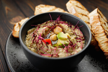 Savory hummus with avocado and tomatoes on a black plate
