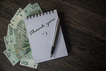 banknoty leżące pod notesem. Wiadomość na kartce notesu: Thank you *)