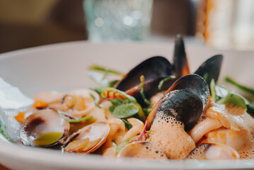 Close up view of the grilled scallop on a plate with mussels.