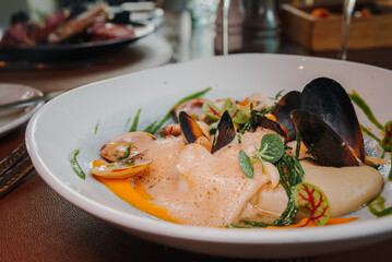 Close up view of the grilled scallop on a plate with mussels.