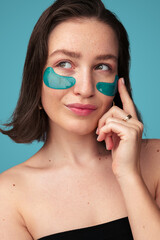 Young woman applying eye patches and looking away