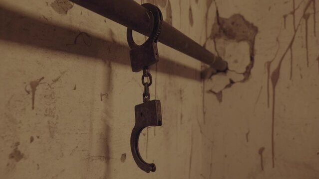 Handcuffs chained to a pipe in an old abandoned building or horror house. High quality FullHD footage