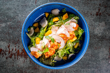 Shrimps salad with arugula, mango and coconut in bowl