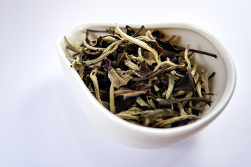 Dry leaves of white tea in a white bowl close-up. Selective focus