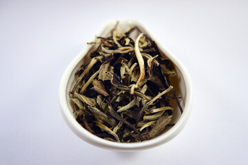 Fototapeta premium Dry Chinese white tea in a white porcelain bowl close-up