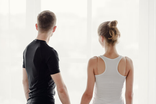 Back view of two athletic young people posing together in light studio, image promoting health, wellness and fitness.