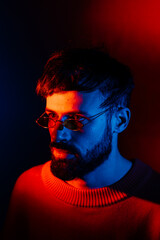 stylized portrait of a man with a beard and black modern glasses using 2 sources of colored light