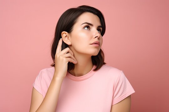 Portrait of a young woman in pink t-shirt looking up thinking, isolated on pink background. Ai generative.
