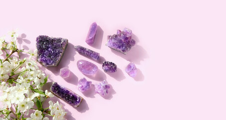 amethyst minerals set and white flowers close up on abstract light pink background. gemstones for esoteric spiritual practice, Crystal Ritual, Witchcraft. top view. copy space. template for design