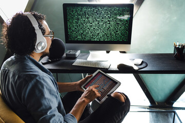 latin man programmer writing program code on desktop computer sitting at the workplace at home in...