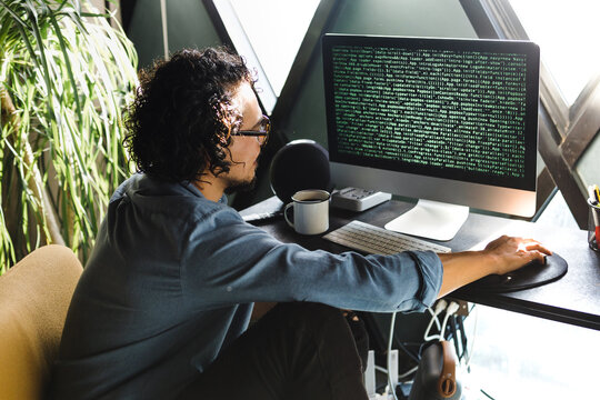 latin man programmer writing program code on desktop computer sitting at the workplace at home in Mexico Latin America, hispanic people