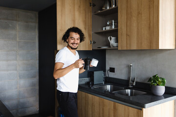 latin young man preparing coffee for breakfast in kitchen at home in Mexico Latin America, hispanic people