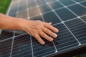 Close up on female hand touching stroking photovoltaic solar panels in sunny day, renewable clean...