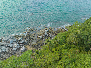 .aerial top view the rock beach full of stones in several size along around the island. .smooth waves hit on the rocks beside the green sea..green water background.