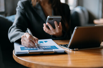 business documents on office desk with laptop and smart phone and graph business diagram and man working in morning light.