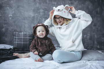 Portrait of family wearing hoodies with bear heads on hoods. Young woman mother touching ears, playing with daughter.