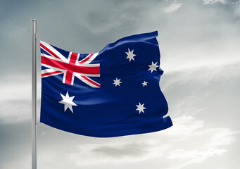 Australia national flag cloth fabric waving on beautiful sky Background.