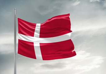 Denmark national flag cloth fabric waving on beautiful sky Background.