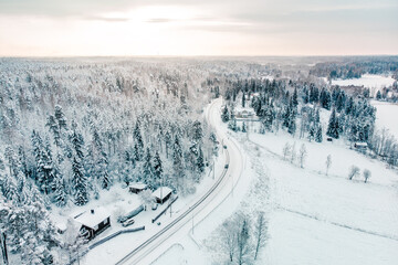 Fototapeta premium Aerial shot of a landscape covered with snowy pine forests and a village in winter