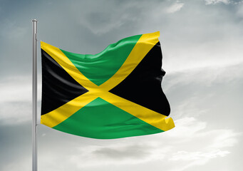 Jamaica national flag cloth fabric waving on beautiful sky Background.