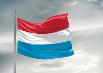 Fototapeta na wymiar Luxembourg national flag cloth fabric waving on beautiful sky Background.