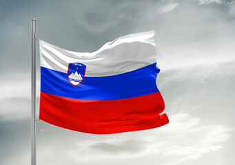 Slovenia national flag cloth fabric waving on beautiful sky Background.
