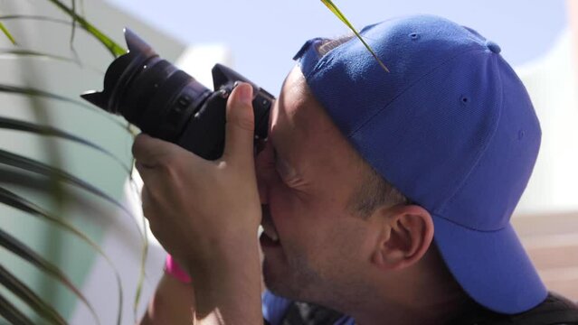 Closeup of a male photographer in a blue cap taking pictures outside on a sunny day