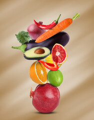 Stack of different vegetables and fruits on pale light brown background