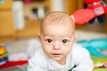 Newborn baby spending tummy time in their playground, baby gym to develop motor skills and strengthen head and neck muscles. baby development and dexterity concept