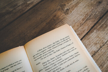 Detail of pages of an open book on a wooden table. Vintage style, overhead shot. Appeals to...