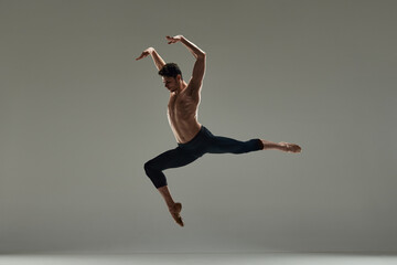 Young handsome man with muscular shirtless body, ballet dancer making performance over grey studio background. Concept of art, classical dance, inspiration, creativity, fashion, beauty, choreography - obrazy, fototapety, plakaty