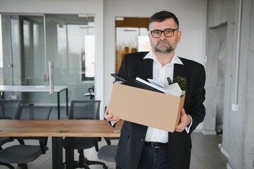 Portrait of sad dismissed senior old business man worker taking his office supplies in the box. Pensioner mature retire from work carry staff back home. Lifestyle business retirement, quit job concept